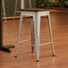 A Lancaster Table & Seating silver metal backless counter height stool with a walnut wood seat.