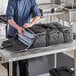 A black Vollrath catering bag holding metal sheet pans.