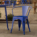 A Lancaster Table & Seating distressed blue metal arm chair on a stone patio.