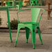 A Lancaster Table & Seating distressed jade green outdoor arm chair on a stone surface.