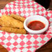 A basket of fried fish sticks with a cup of red sauce.