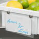 a white container with a white sign and a bunch of limes