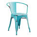 A Lancaster Table & Seating distressed turquoise metal arm chair with black legs.