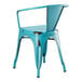 A Lancaster Table & Seating distressed turquoise metal arm chair on an outdoor patio.