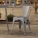 A Lancaster Table & Seating metal chair and table on an outdoor patio.