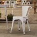 A Lancaster Table & Seating distressed white outdoor arm chair on a patio.