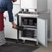 An Avantco worktop refrigerator with a man opening a black container.