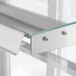 A close up of a metal shelf with two screws inside a white refrigerated bakery display case.
