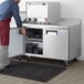 A man in a red apron using an Avantco worktop freezer.