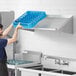 A man holding a blue plastic basket of dishes on a Regency wall mounted slanted rack shelf.