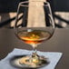 A Stolzle brandy snifter filled with brown liquid on a table