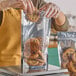 A person putting a cookie in a Choice clear plastic zip top pouch.