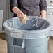 A person throwing paper into a trash can.