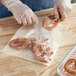 A person in plastic gloves holding a Choice clear polyethylene bag of pretzels.