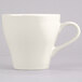 A close-up of a Tuxton Europa eggshell white coffee cup with a white handle.