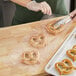 A person using tweezers to put a pretzel in a clear plastic bag.