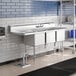 A Regency stainless steel three compartment sink with a drainboard on a counter.