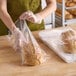 A person holding a loaf of bread in a Choice clear plastic bag.