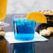 A blue drink in a WNA Comet Classicware clear plastic tumbler with a slice of orange.