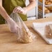 A woman in a green apron using a Choice clear plastic bag to package a loaf of bread.