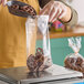 A woman using a clear gusseted polyethylene bag to put chocolate chips into a bag.