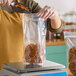 A woman pouring pretzels into a Choice clear zip top pouch.