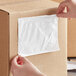 A person's arm putting a Lavex clear polyethylene envelope in a box.