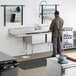 A man standing in a commercial kitchen with a Regency two compartment sink with a left drainboard.