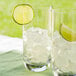 Two glasses of ice with lime wedges next to a bowl of ice cubes.