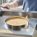 A hand using a Choice stainless steel egg ring to cook eggs on a pan.
