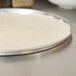 A pizza dough on an American Metalcraft aluminum pizza pan.