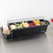 A San Jamar condiment bar with fruit and cherries in containers on a counter.