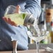 A person using an Acopa glass mason jar cocktail shaker to pour a drink into a glass.