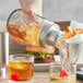 A person using an Acopa Mason Jar Cocktail Shaker to pour a drink into a glass.