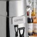 A silver coffee chafer urn with a "Coffee" label on a chain.