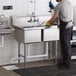 A man in an apron and gloves washing a Regency two compartment commercial sink.