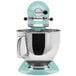 A blue and silver KitchenAid Artisan Series countertop mixer in a bowl.