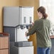 A woman using a Scotsman countertop ice machine and water dispenser to fill a cup with water.