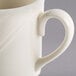 A close-up of a Homer Laughlin ivory china mug with a curved handle.