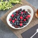 A 10 Strawberry Street Whittier white porcelain bowl with cut outs holding a bowl of berries on a table.