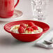 A Tuxton Concentrix cayenne grapefruit bowl filled with food with raspberries and nuts.