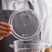 A hand holding a clear lid over a clear food storage container.