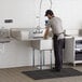 A man standing in a professional kitchen washing a Regency stainless steel sink.