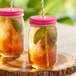 Two Acopa Rustic Charm drinking jars filled with a liquid and a straw.