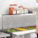 A woman standing in a school kitchen with a ServIt single overshelf on a counter.