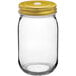 An Acopa clear glass drinking jar with a gold metal lid.