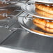 A rack of metal trays with pizzas inside an Alto-Shaam hot holding cabinet.
