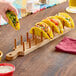 A group of tacos on an American Metalcraft acacia wood holder.