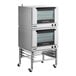 A double deck full size electric convection oven with mechanical controls and casters.