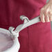 A hand using a Choice aluminum pail opener to open a white bucket.